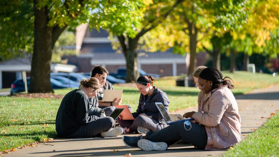 学生们坐在校园购物中心的人行道上